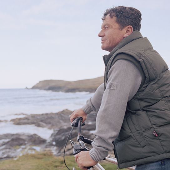 A man stopped on a bike at a cliff overlooking the ocean
