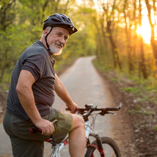 Older male resting on bike in the woods