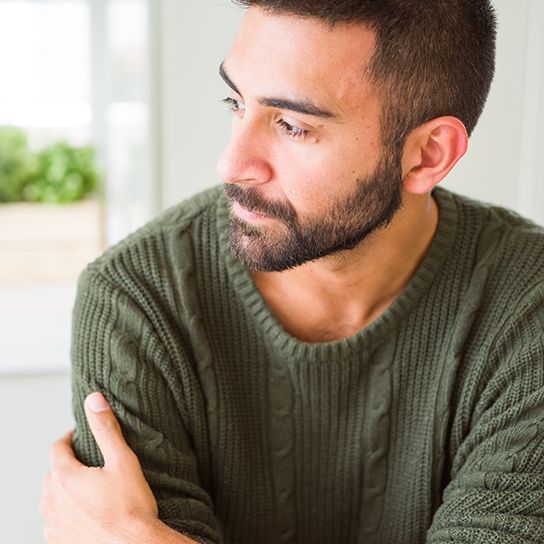 Close up of man leaning forward with arms crossed, looking to the side