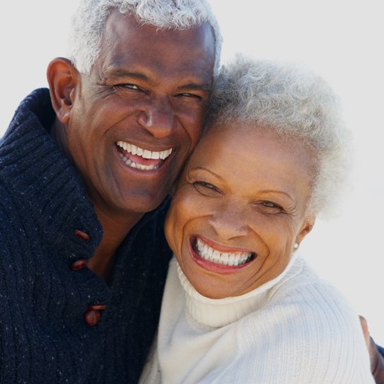 An older man and woman pressing their faces together and smiling 
