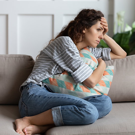 Woman curled on couch, looking distraught
