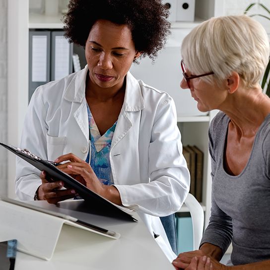 Woman doctor showing older woman patient something on a clipboard